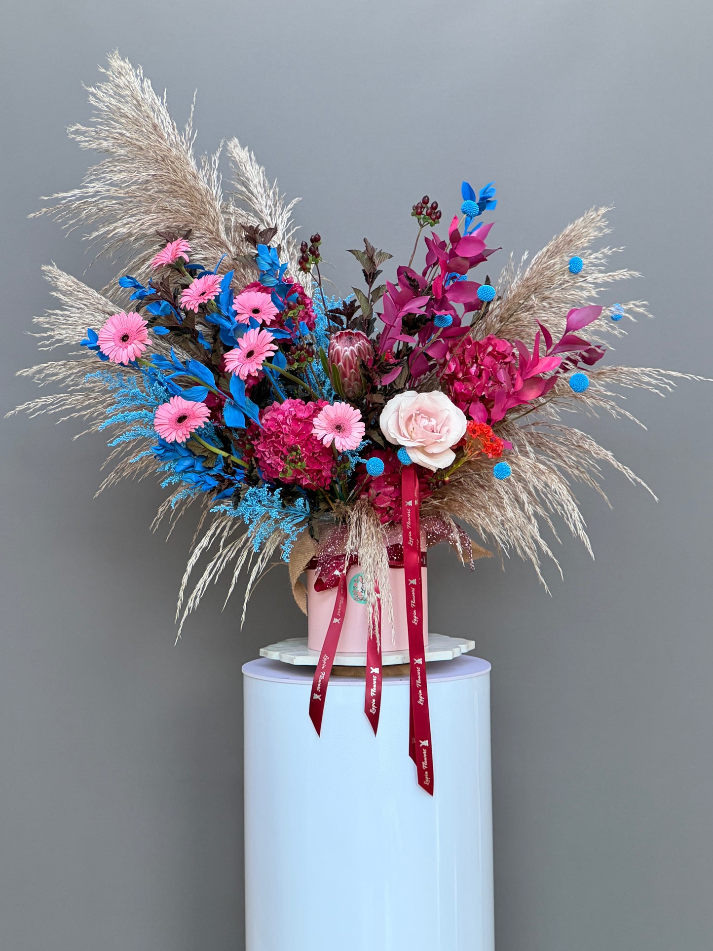 Bohemian Rhapsody dramatic king protea and pampas grass hatbox arrangement in studio lighting luxury flower delivery Potomac MD Bethesda McLean Washington DC Lapin Flowers