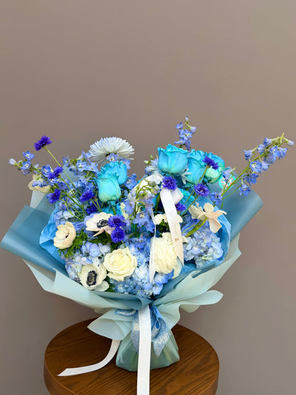 Bouquet for honor of John Hopkins.
Extra-large luxury artisan flower bouquet featuring premium dyed blue roses, white anemones with black centers, blue delphinium, and blue hydrangea wrapped in ice-blue paper by Lapin Flowers. Upscale elite floral design for delivery in Maryland, Washington DC, and Virginia.⁠