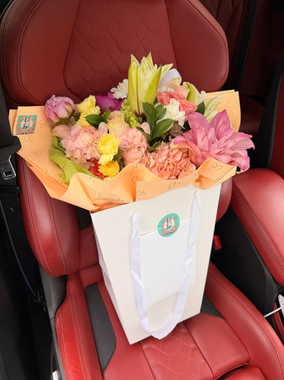 Extra-large luxury artisan flower bouquet with a double pink lily, blush pink hydrangea, garden roses, and pastel carnations wrapped in peach and green paper by Lapin Flowers. Upscale elite delivery for Potomac Maryland and Washington DC.
