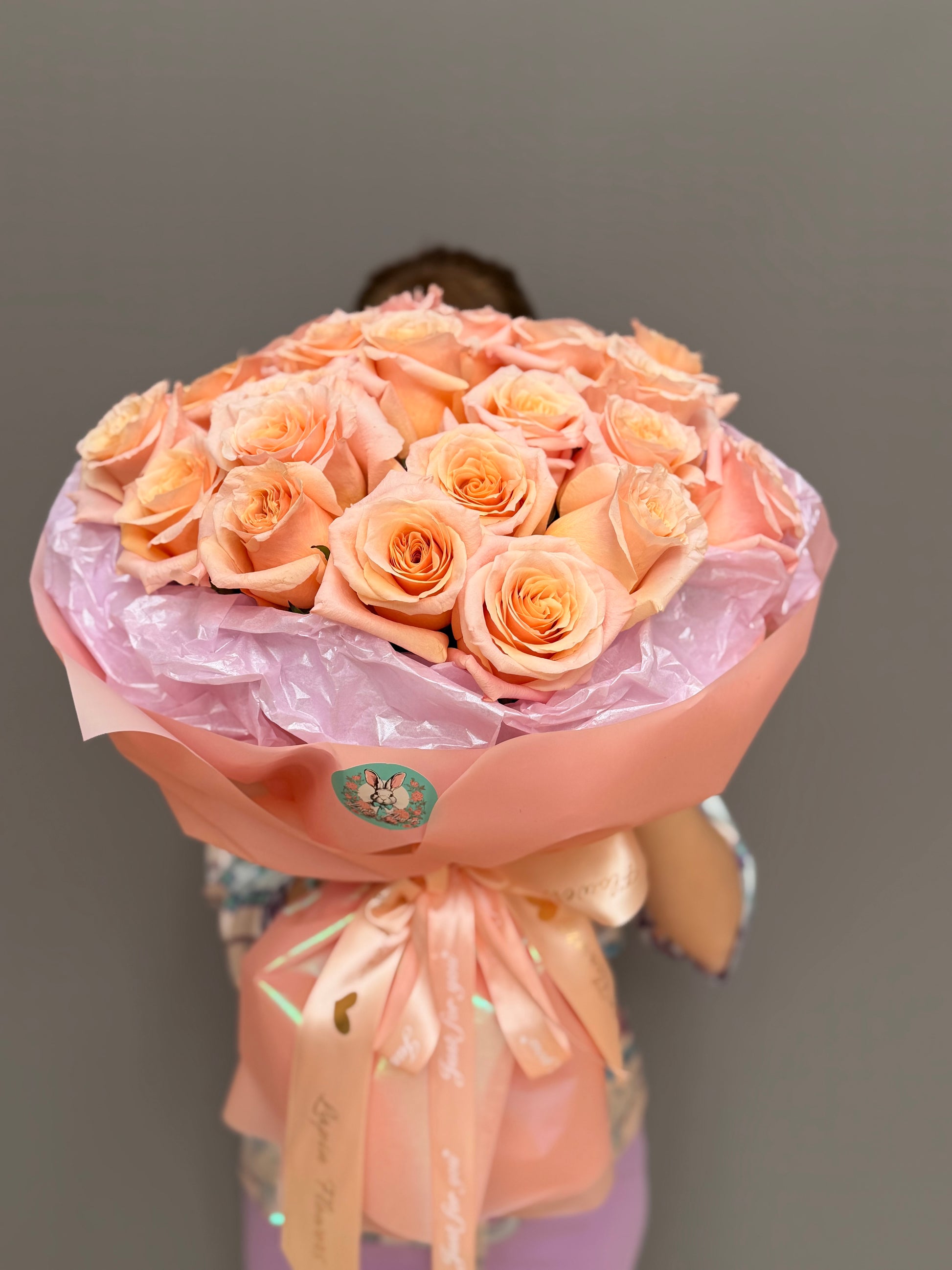 Top-down view of a lush peach rose mono-bouquet wrapped in blush paper from Lapin Flowers in Howard County Maryland.