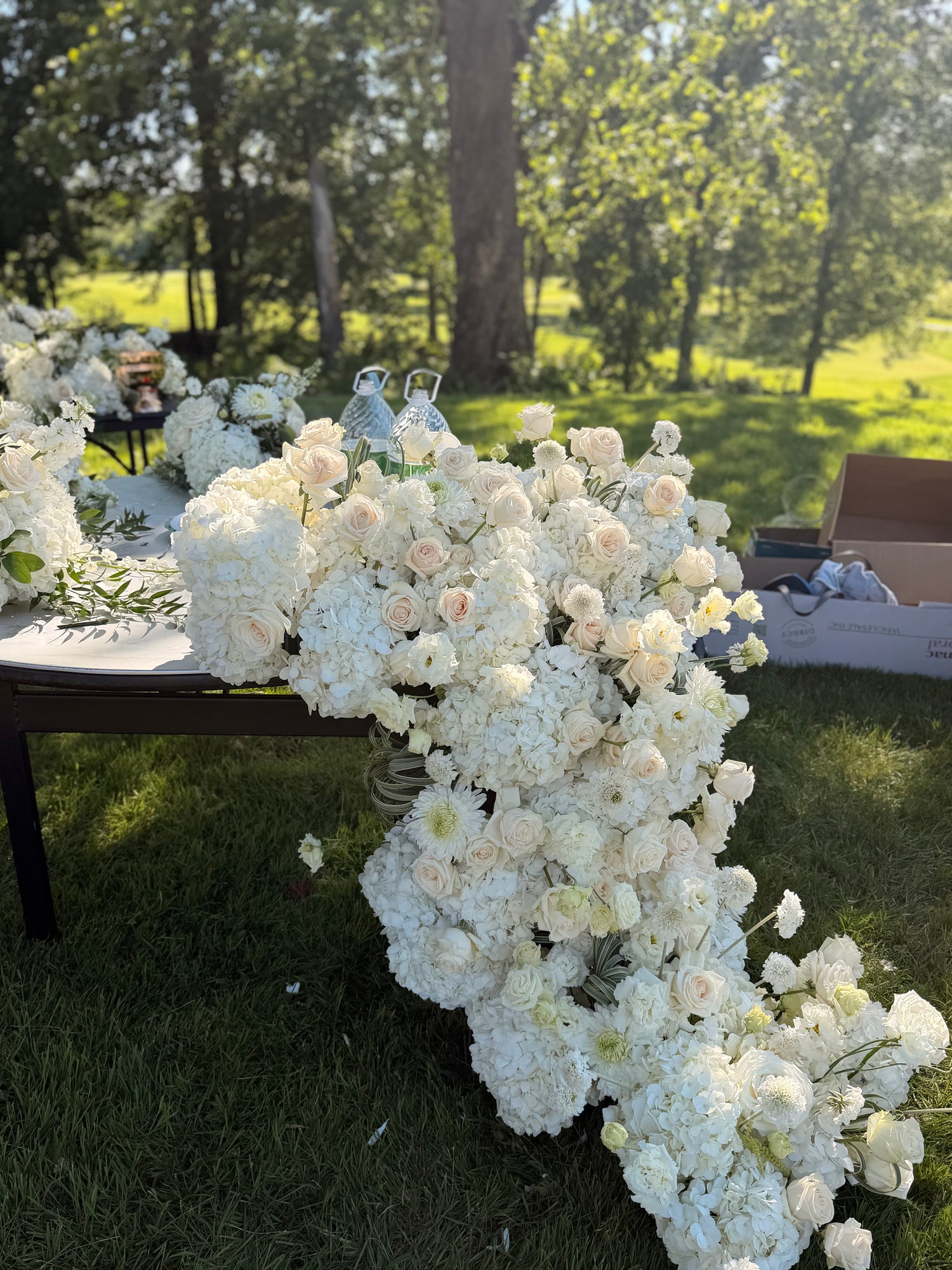 Grand luxury wedding floral installation featuring a dense table runner with white hydrangeas and blush roses cascading down onto the grass by Lapin Flowers. Premium elite event design expertly curated for Washington DC, Potomac, Bethesda, Rockville, and the historic waterfront estates of Annapolis, Maryland. Serving the premier corporate hubs and high-end residential enclaves of Northern Virginia, including Tysons, McLean, Great Falls, Arlington, and Alexandria.