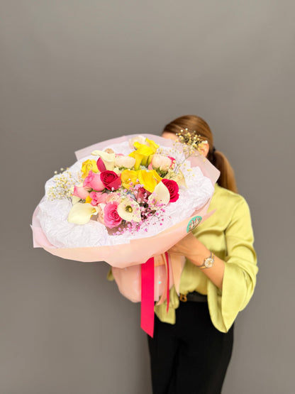 Large luxury mixed bouquet with yellow calla lilies, white calla lilies, magenta roses, and ranunculus wrapped in a big white tissue cloud held by a person by Lapin Flowers. Premium elite event floral design for Washington DC and Potomac MD, McLean VA, Bethesda MD, Annapolis MD. 