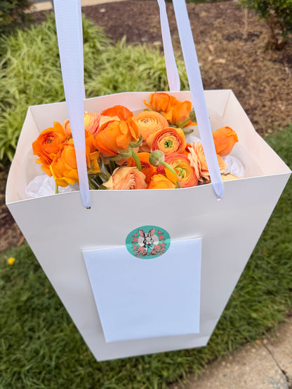 Luxury monochrome flower bouquet with 30 orange and peach ranunculus in a premium white gift bag with handles by Lapin Flowers. Upscale chic flower delivery for Bethesda Maryland and Washington DC.