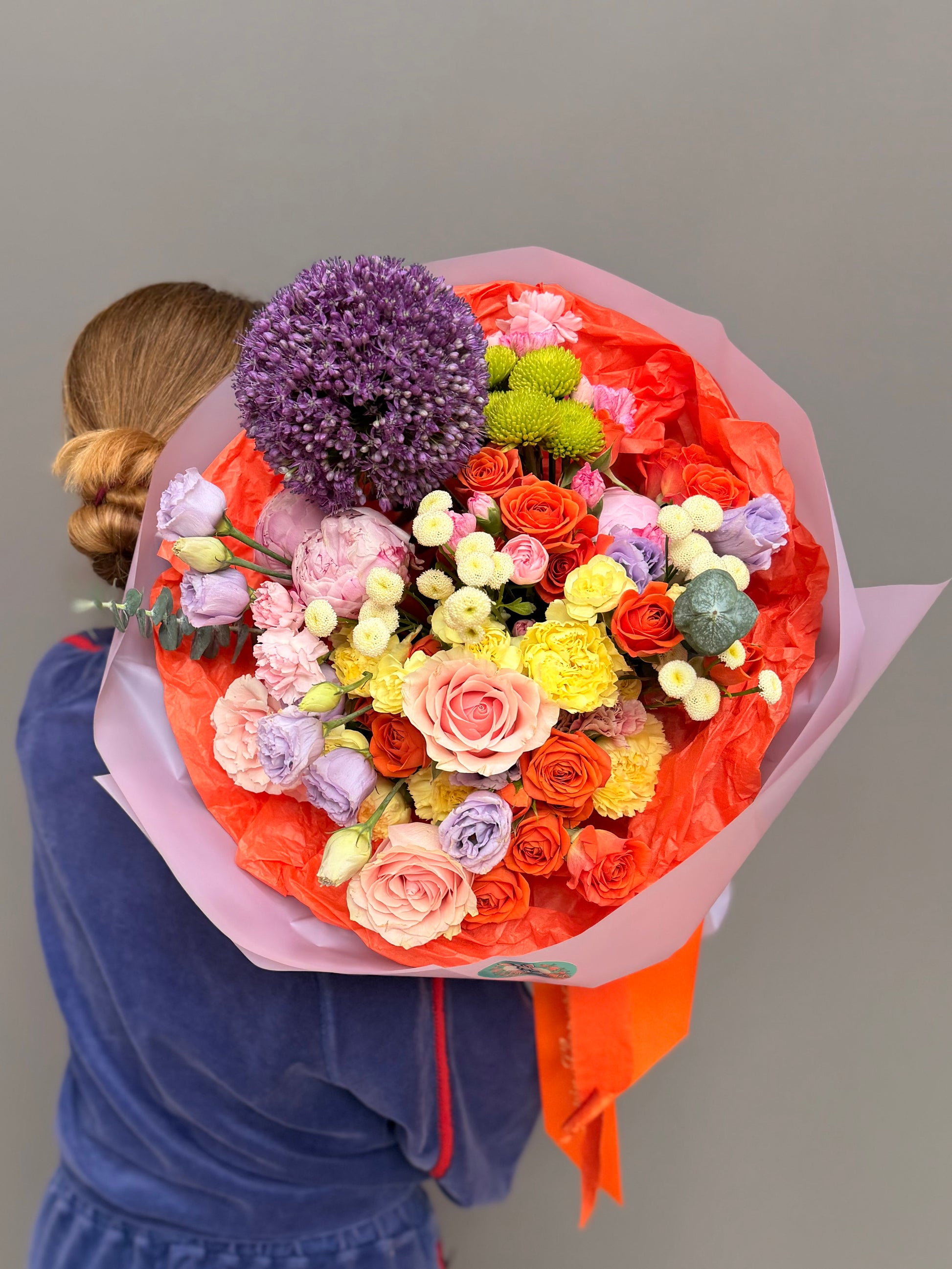 Extra-large luxury artisan bouquet featuring a giant purple Allium, coral and orange roses, lavender lisianthus, and white button flowers wrapped in a vibrant orange and lilac paper by Lapin Flowers. Premium flower delivery in Maryland, Washington DC, and Virginia.⁠