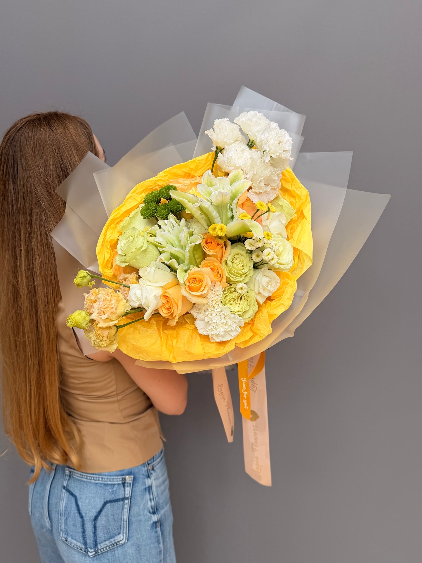 Extra-large luxury artisan flower bouquet with peach roses, white lilies, white lisianthus, and green button mums wrapped in bright yellow and frosted paper by Lapin Flowers. Premium flower delivery for Washington DC and Maryland.⁠