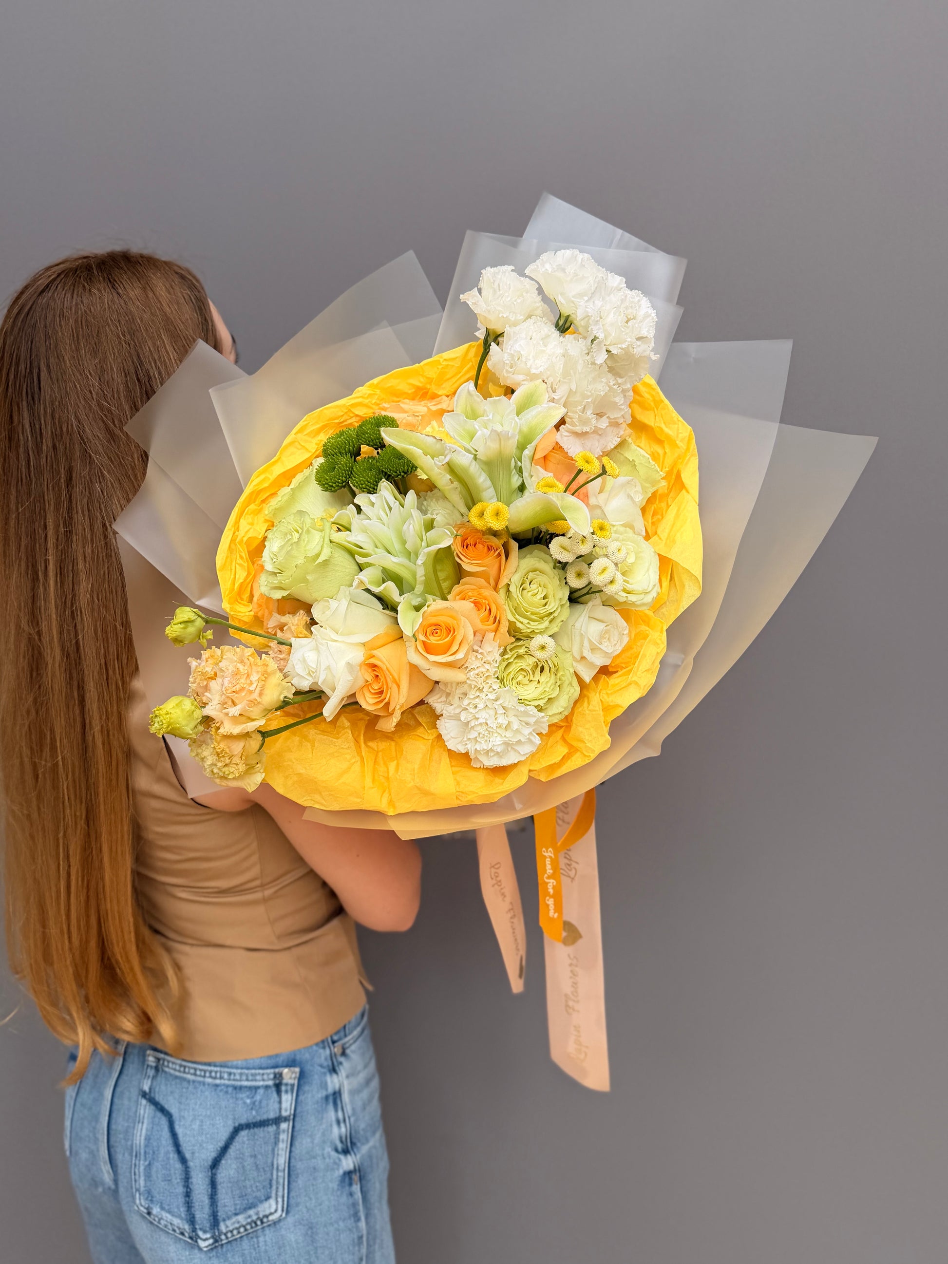 Extra-large luxury artisan flower bouquet with peach roses, white lilies, white lisianthus, and green button mums wrapped in bright yellow and frosted paper by Lapin Flowers. Premium flower delivery for Washington DC and Maryland.⁠