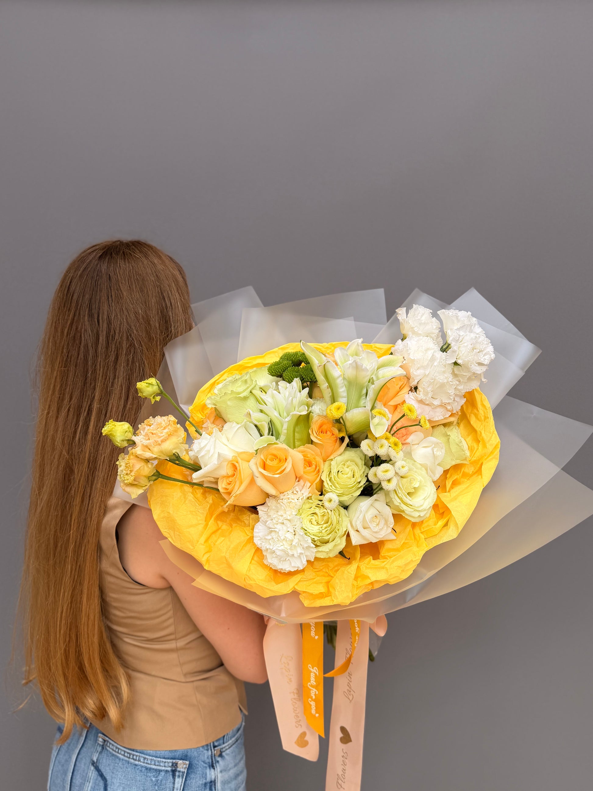 Extra-large luxury artisan flower bouquet with peach roses, white lilies, white lisianthus, and green button mums wrapped in bright yellow and frosted paper by Lapin Flowers. Premium flower delivery for Washington DC and Potomac, MD and McLean, VA.⁠