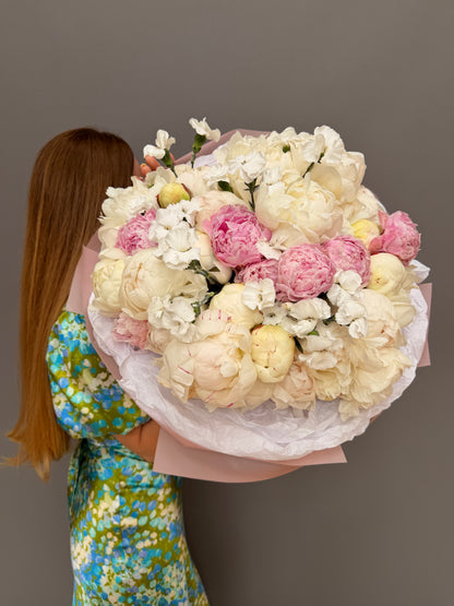 Extra-large luxury artisan bouquet with peach roses, yellow lisianthus, and yellow butterfly ranunculus in a striking yellow and peach wrapping paper by Lapin Flowers, premium flower delivery in Washington DC,  Maryland and Northwest Virginia. 