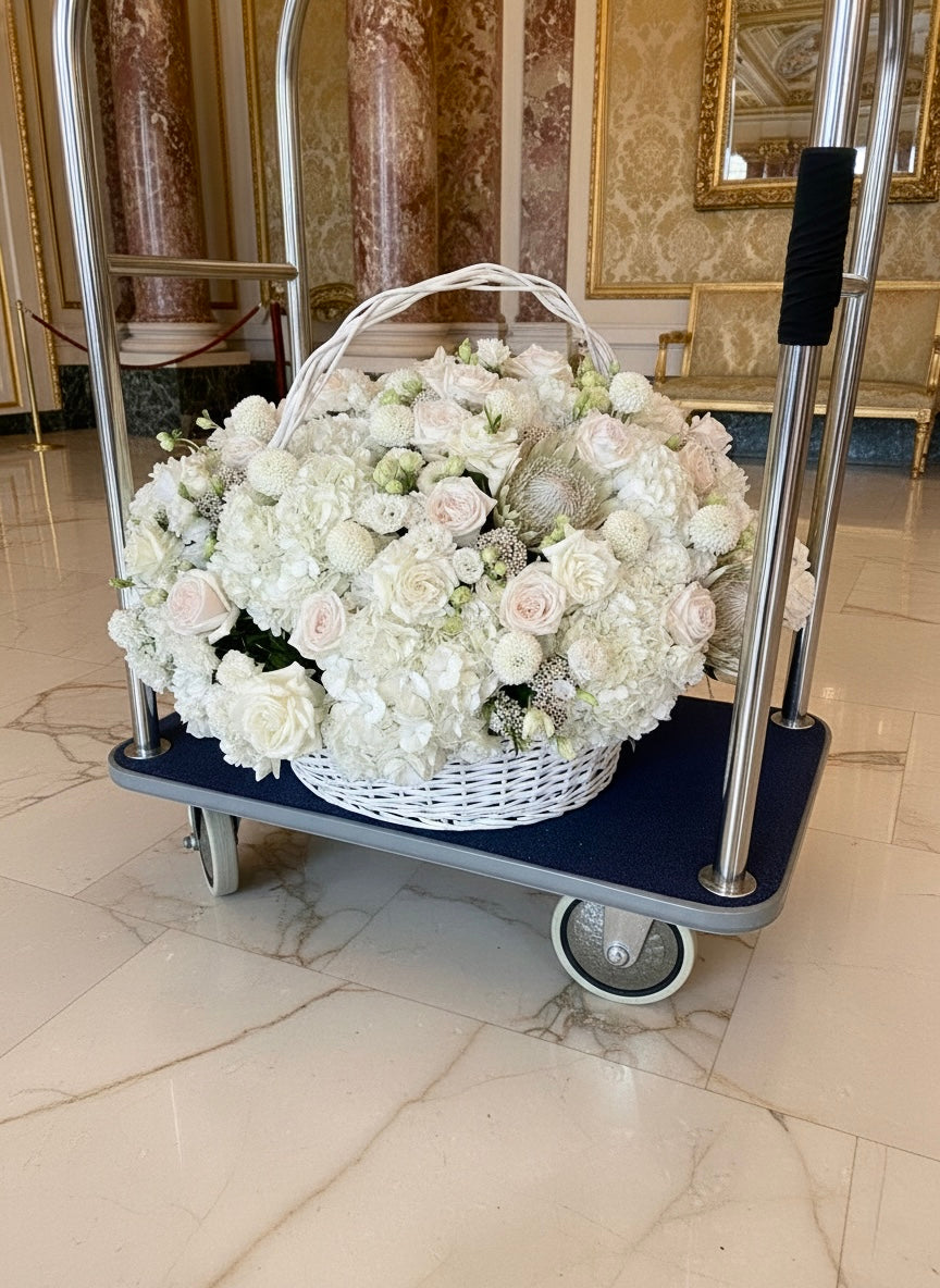 Basket of white flowers on a trolley in an elegant room with marble floors and ornate walls.