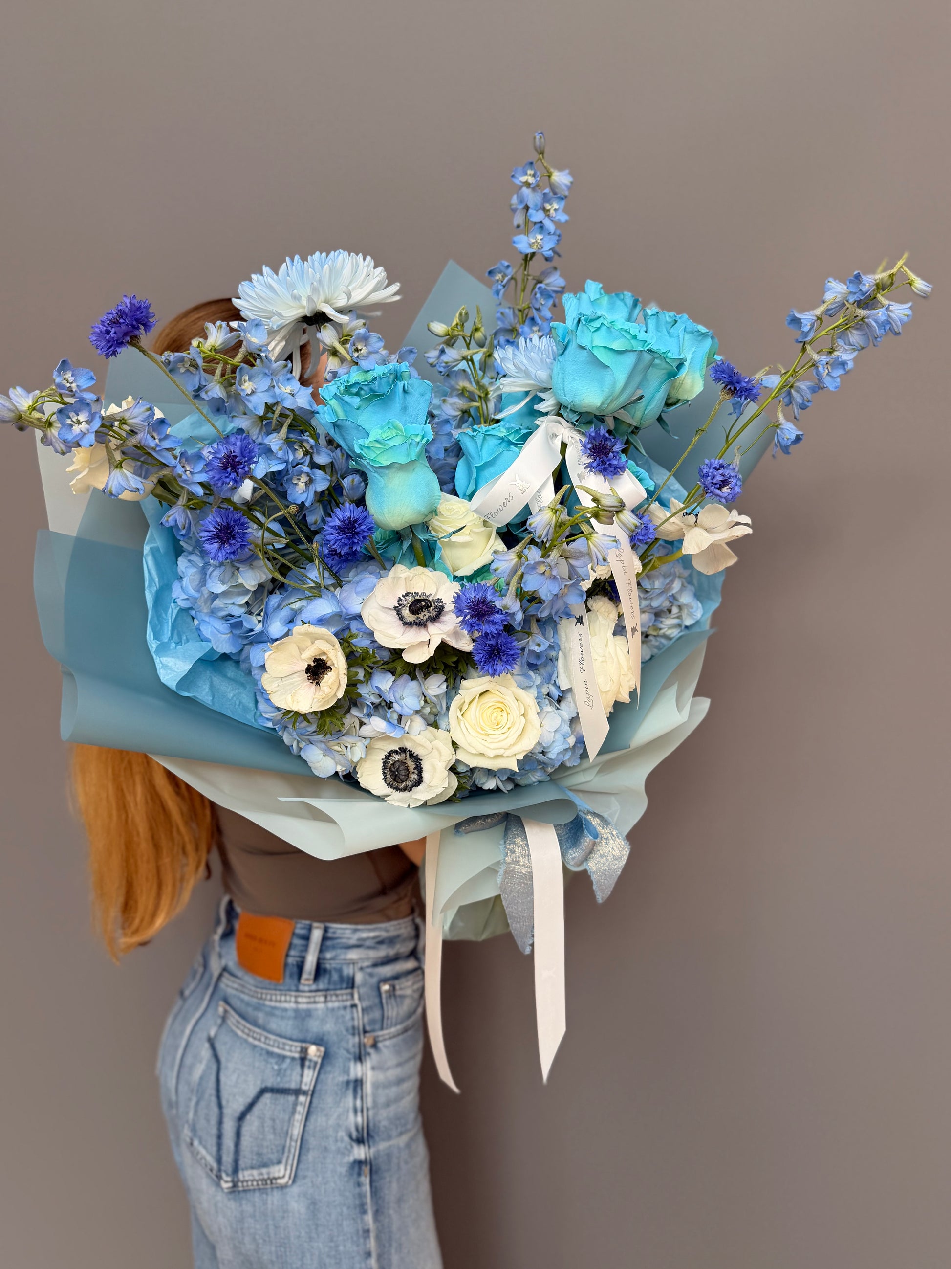 Extra-large luxury artisan flower bouquet featuring premium dyed blue roses, white anemones with black centers, blue delphinium, and blue hydrangea wrapped in ice-blue paper by Lapin Flowers. Upscale elite floral design for delivery in Maryland, Washington DC, and Virginia.⁠