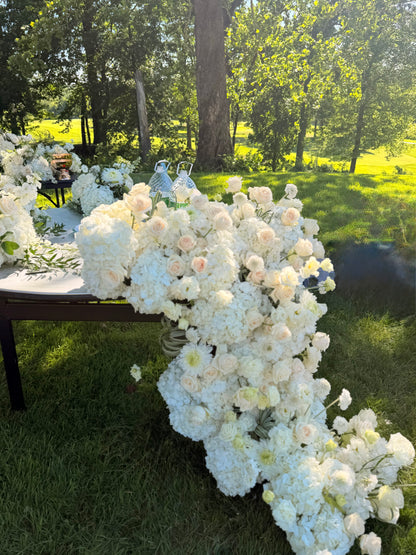 Grand luxury wedding floral installation featuring a dense table runner with white hydrangeas and blush roses cascading down onto the grass by Lapin Flowers. Premium elite event design expertly curated for Washington DC, Potomac, Bethesda, Rockville, and the historic waterfront estates of Annapolis, Maryland. Serving the premier corporate hubs and high-end residential enclaves of Northern Virginia, including Tysons, McLean, Great Falls, Arlington, and Alexandria.