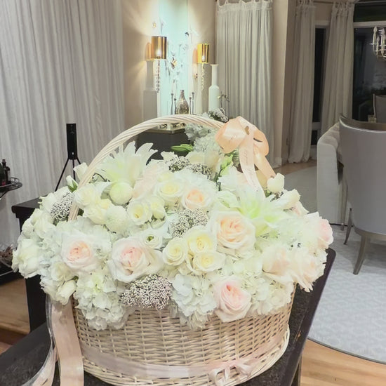 Large-scale luxury white flower basket by Lapin Flowers for an engagement in Maryland. Featuring 25 premium Jumbo white hydrangeas, blush O'Hara garden roses, and white lilies in a 24-inch wicker basket. Professional floral installation for upscale events in the MD, VA, and DC area.