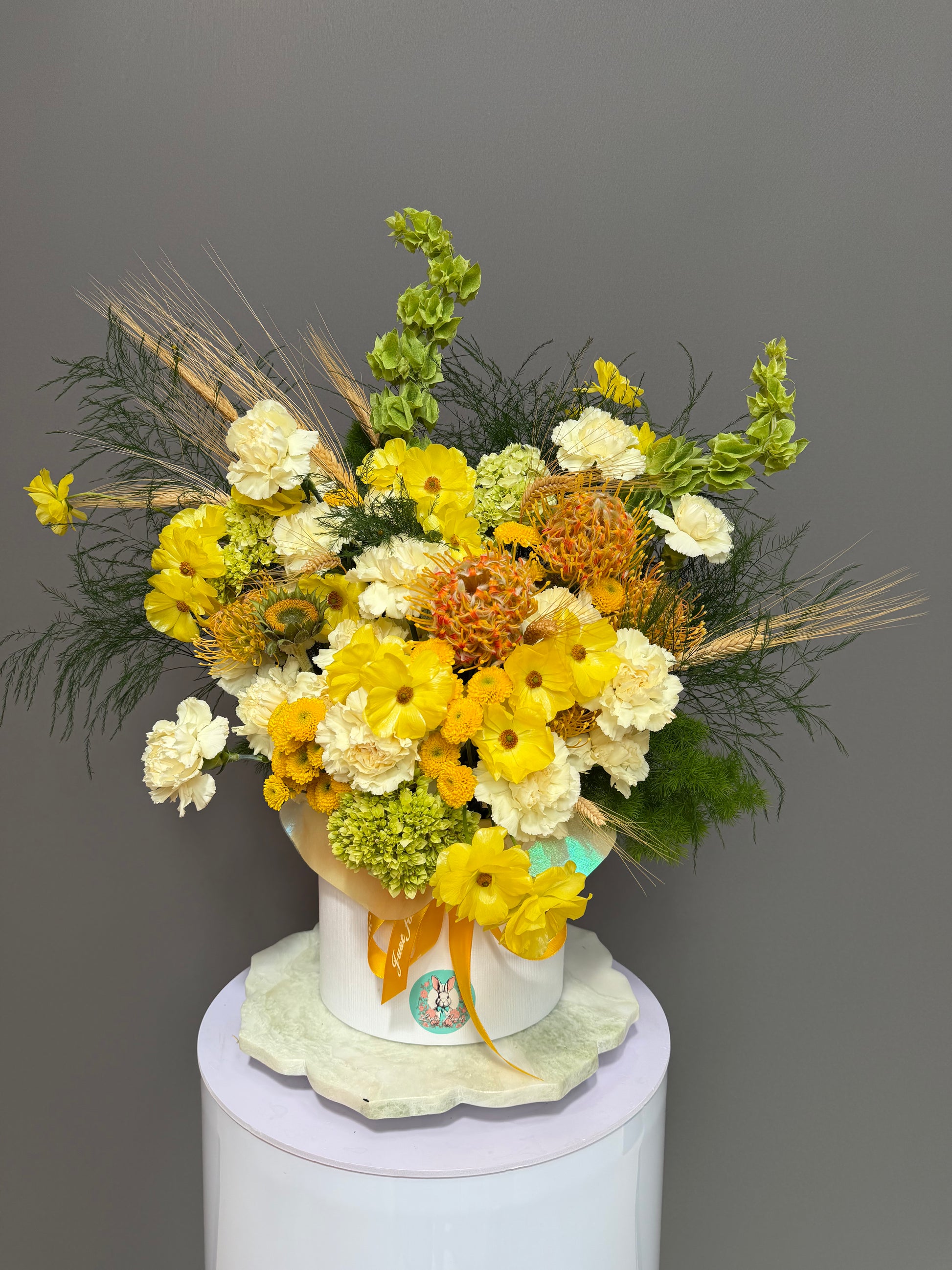Soleil d’Or luxury yellow butterfly ranunculus and protea hatbox arrangement delivery Potomac MD Bethesda McLean Washington DC Lapin Flowers⁠